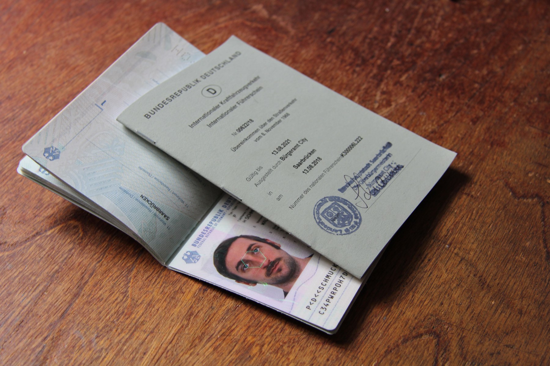 A German passport and an international driving licence on a wooden table